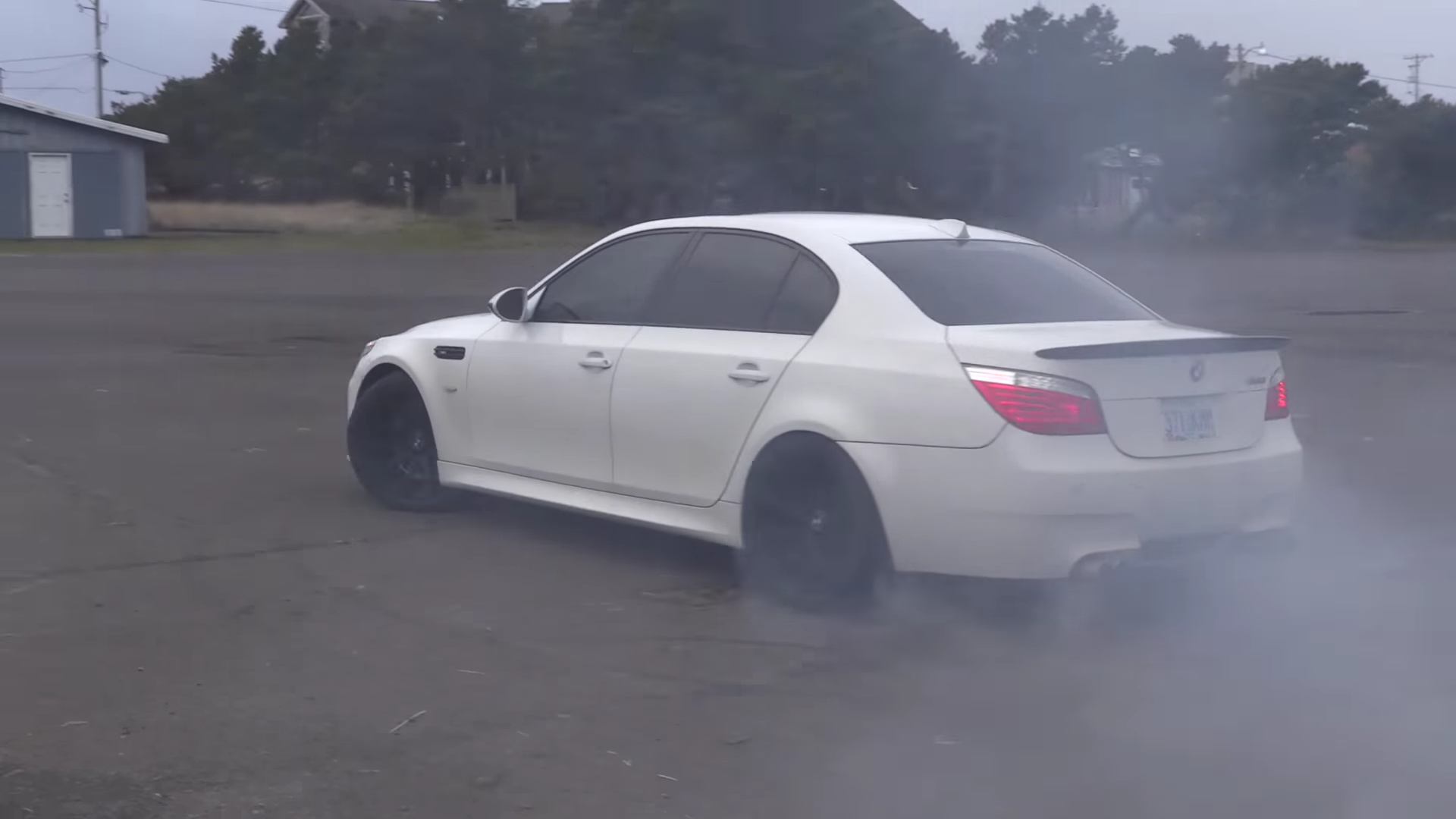 BMW M5 doing some donuts and burning some rubber in a parking lot.